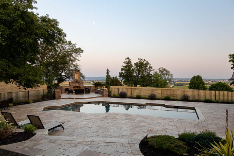 paver patio around a pool with an outdoor fireplace