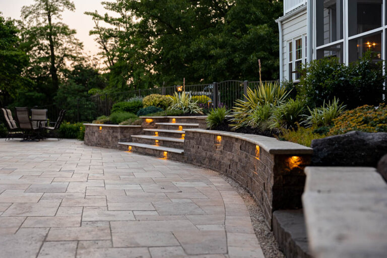 paver patio with a retaining wall with lights
