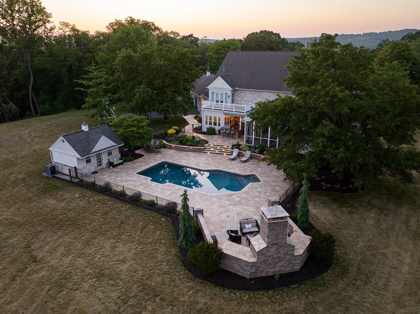 arial view of the paver patio around a pool with an outdoor fireplace