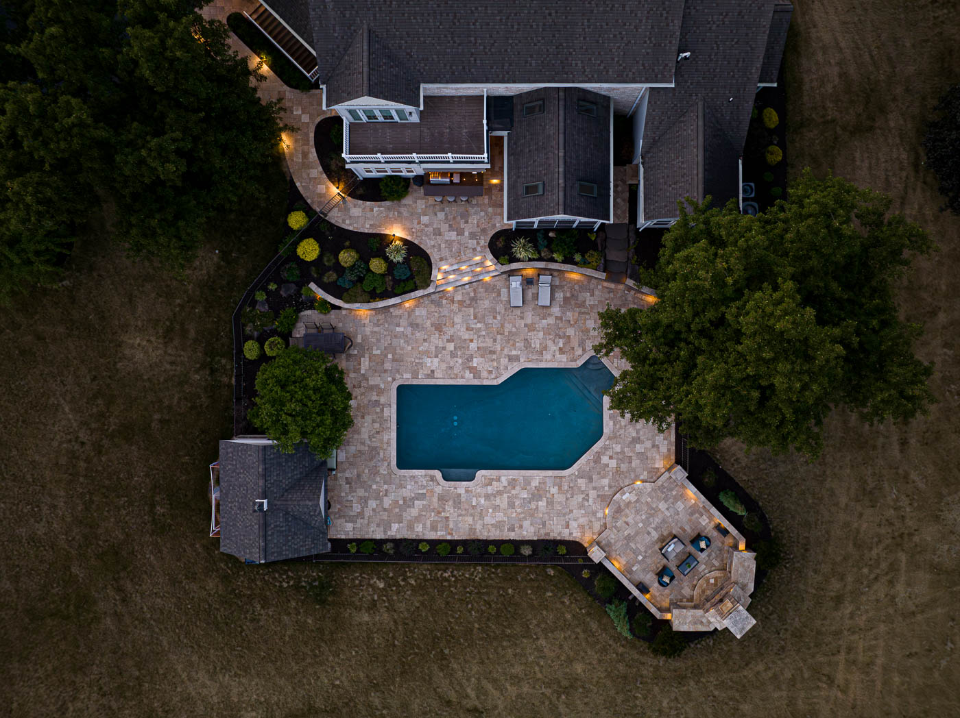 arial view of the paver patio around a pool with an outdoor fireplace