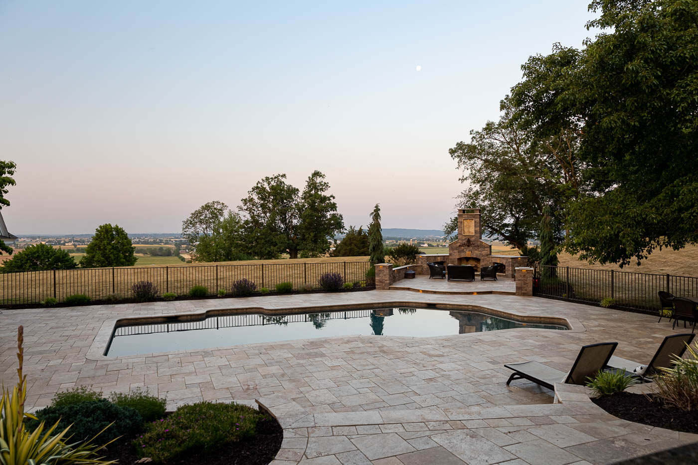 paver patio around a pool with and outdoor fireplace