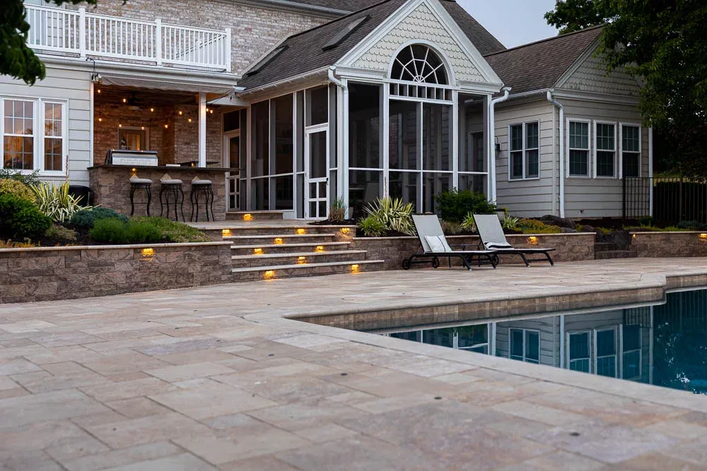 Patio, pool, and steps at dusk with step and porch lights on